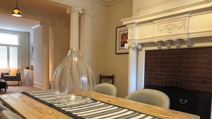 A dining area with a wooden table, striped table runner, and a clear glass vase centerpiece. - Historic Geneva Row House near Hobart William Smith Colleges and Linden Street. (Geneva)