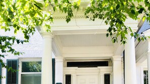 A white building with a front door, steps, and a black railing. - Historic Geneva Row House near Hobart William Smith Colleges and Linden Street. (Geneva)