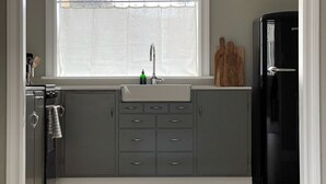 A kitchen with a window, a sink, cabinets, a refrigerator, and wooden cutting boards on the counter. - Design apartments in Reykjavik (Reykjavik)