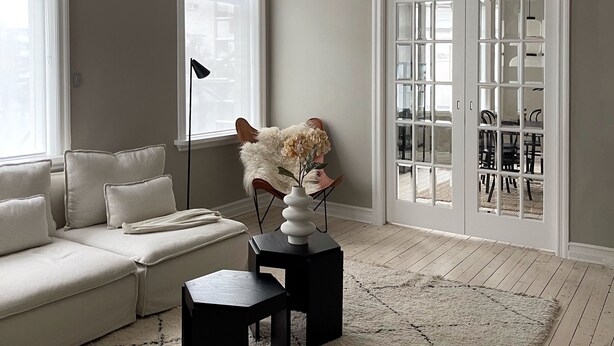 A living room with a sofa, a coffee table, a vase with flowers, a pendant light, and a view through a glass door to an outdoor area. - Design apartments in Reykjavik (Reykjavik)