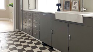 A kitchen with grey cabinets, a checkered floor, a window with curtains, and a sink with a faucet. - Design apartments in Reykjavik (Reykjavik)