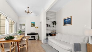 Uma sala de estar espaçosa com uma mesa de jantar, sofá branco e uma estante de livros.