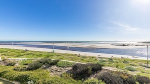 A coastal landscape with a beach, a river, and a clear sky.