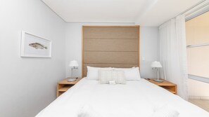 A neatly arranged hotel room with a large bed, two bedside tables, a headboard, and a window with curtains. - Lagoon Beach Gem Pool, Views & sea breeze (Milnerton)