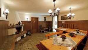 Ett traditionellt matrum med en öppen spis, möbler i trä och en kristallkrona.