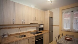A kitchen with wooden cabinets, a stainless steel sink, a microwave, and a refrigerator.