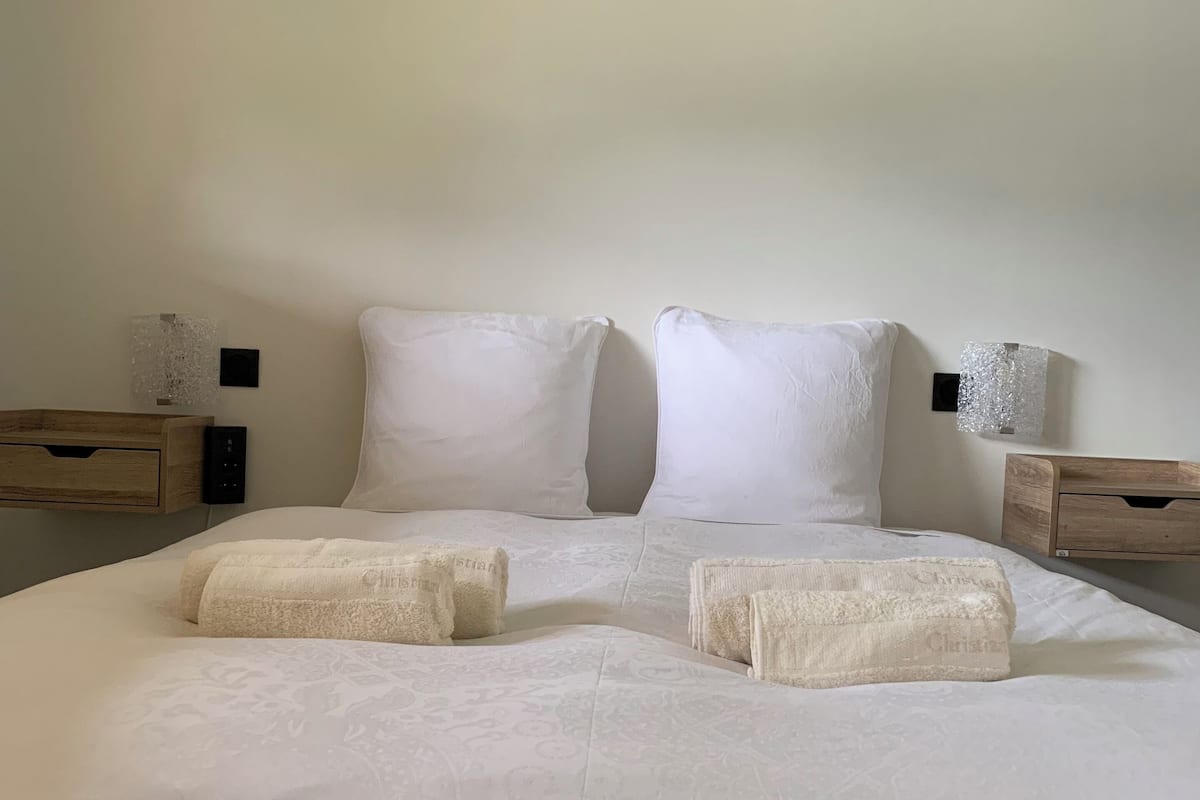 A neatly made bed with two pillows and two folded towels.