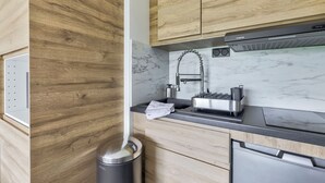 A modern kitchen with wooden cabinets, a marble backsplash, and stainless steel appliances. - La Parenthèse Enchantée (Sevrier)