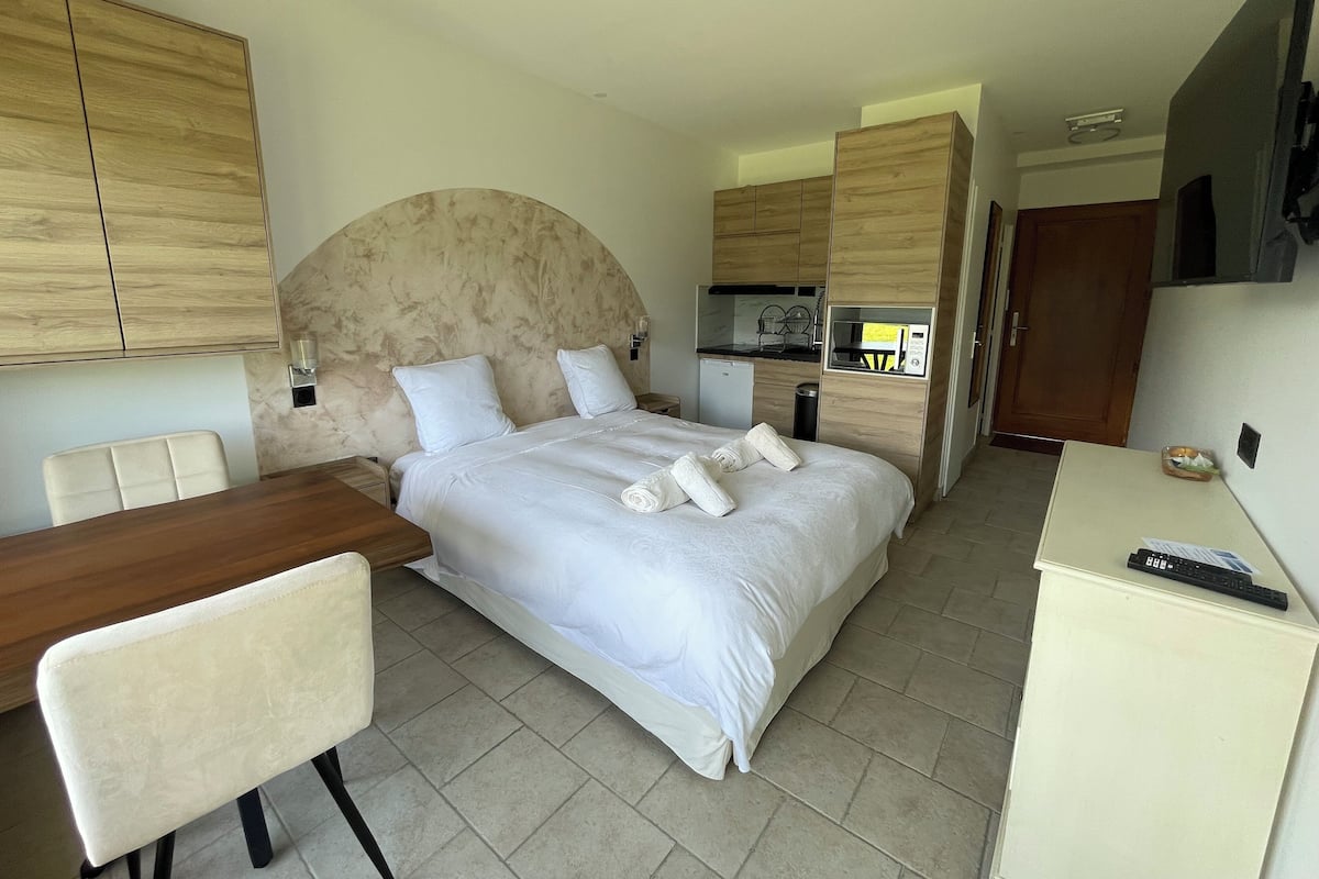 A hotel room with a bed, a desk, a chair, a microwave, and a television.