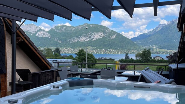 A hot tub with a control panel, surrounded by outdoor furniture and a mountain view. - La Parenthèse Enchantée (Sevrier)