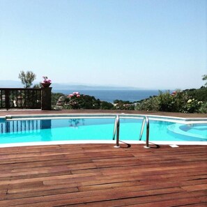 A swimming pool with a wooden deck and a view of the sea. - Luxury Villa Jasmine w Private Pool (Skiathos)