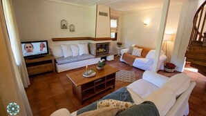 Ein gemütliches Wohnzimmer mit Kamin, Fernseher und Wendeltreppe.