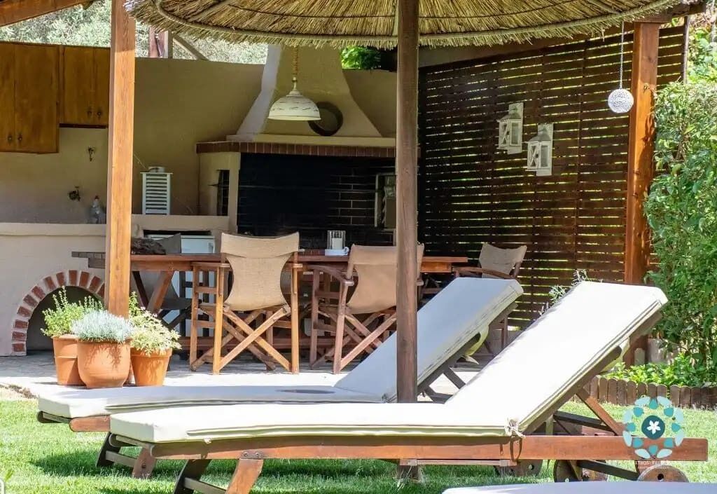 Un patio al aire libre con mesa de madera, sillas y sillones de descanso.