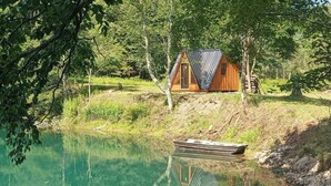 Una cabaña de madera junto a un lago tranquilo, rodeada de árboles.