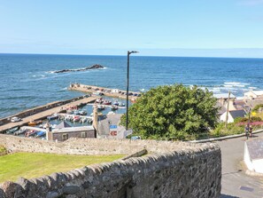 A coastal marina with boats docked, a stone wall, and a clear view of the sea. - 111a Main Street (Banff)
