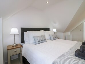 A neatly arranged bedroom with a large bed, two bedside tables, and a radiator. - 111a Main Street (Banff)