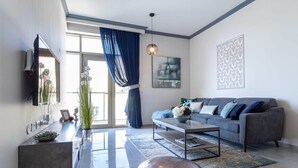 A modern living room with a grey sofa, a coffee table, and a TV mounted on the wall.
