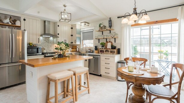 A modern kitchen with a central island, stainless steel appliances, and a dining area with a wooden table and chairs.