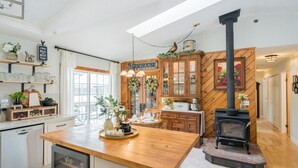 A kitchen with a farmhouse theme, including wooden cabinets, a central island, and a wood-burning stove.