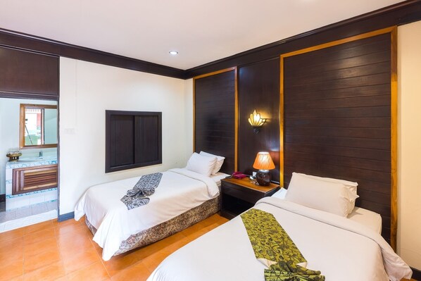 A hotel room with two beds, a wooden headboard, a nightstand with a lamp, and a view of the outside. - Huen Khum Resort Boutique (Mae Sai)