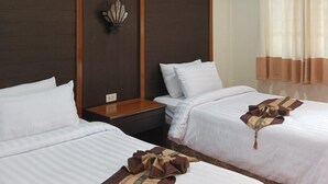 Een hotelkamer met twee bedden, houten hoofdborden, een wandlamp en een raam met gordijnen.