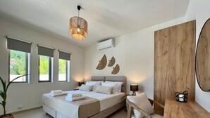 Un dormitorio moderno con cama, mesita de noche, silla y un amplio ventanal.