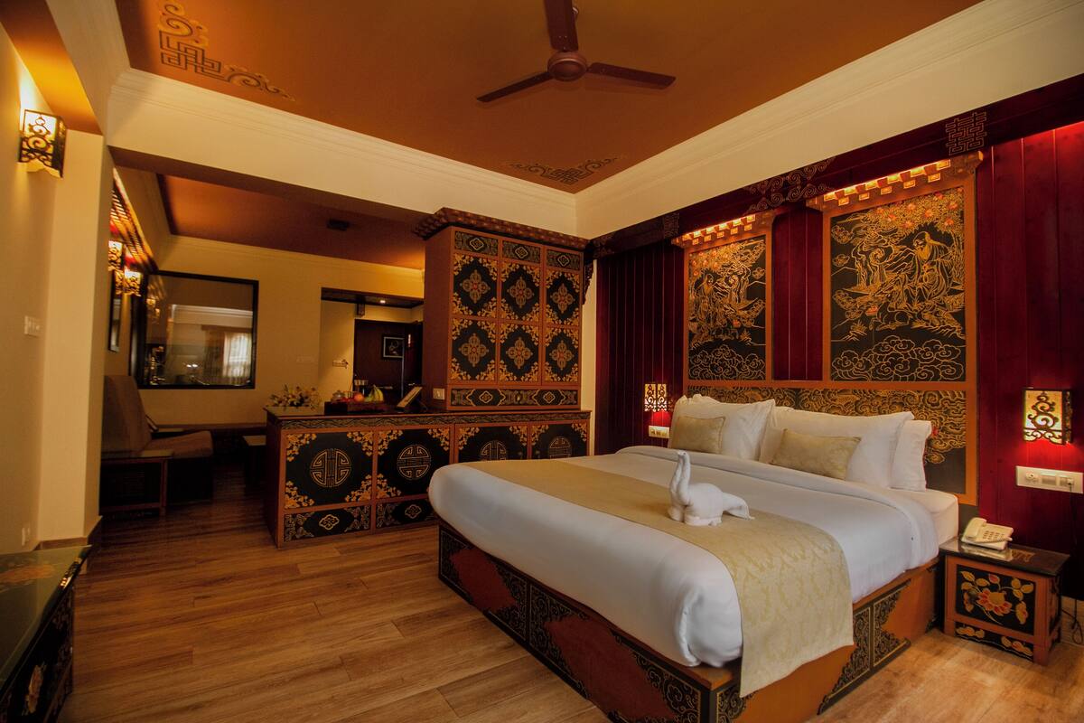 A traditional room with a large bed, wooden furniture, and intricate wall decorations.