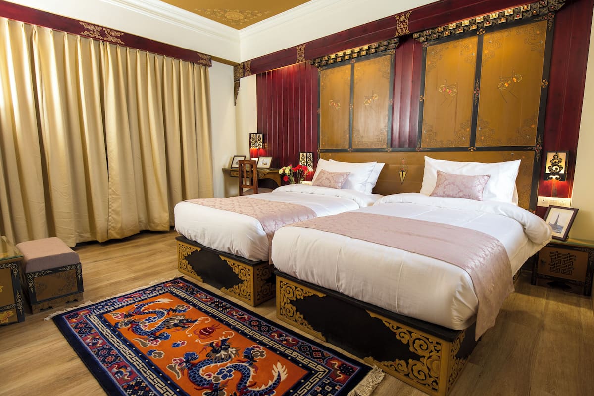 A double bed with a wooden headboard, a bedside table with a lamp, and a decorative rug.