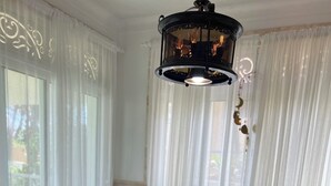 A dining table set with blue glassware, plates, and napkins, with a chandelier above.