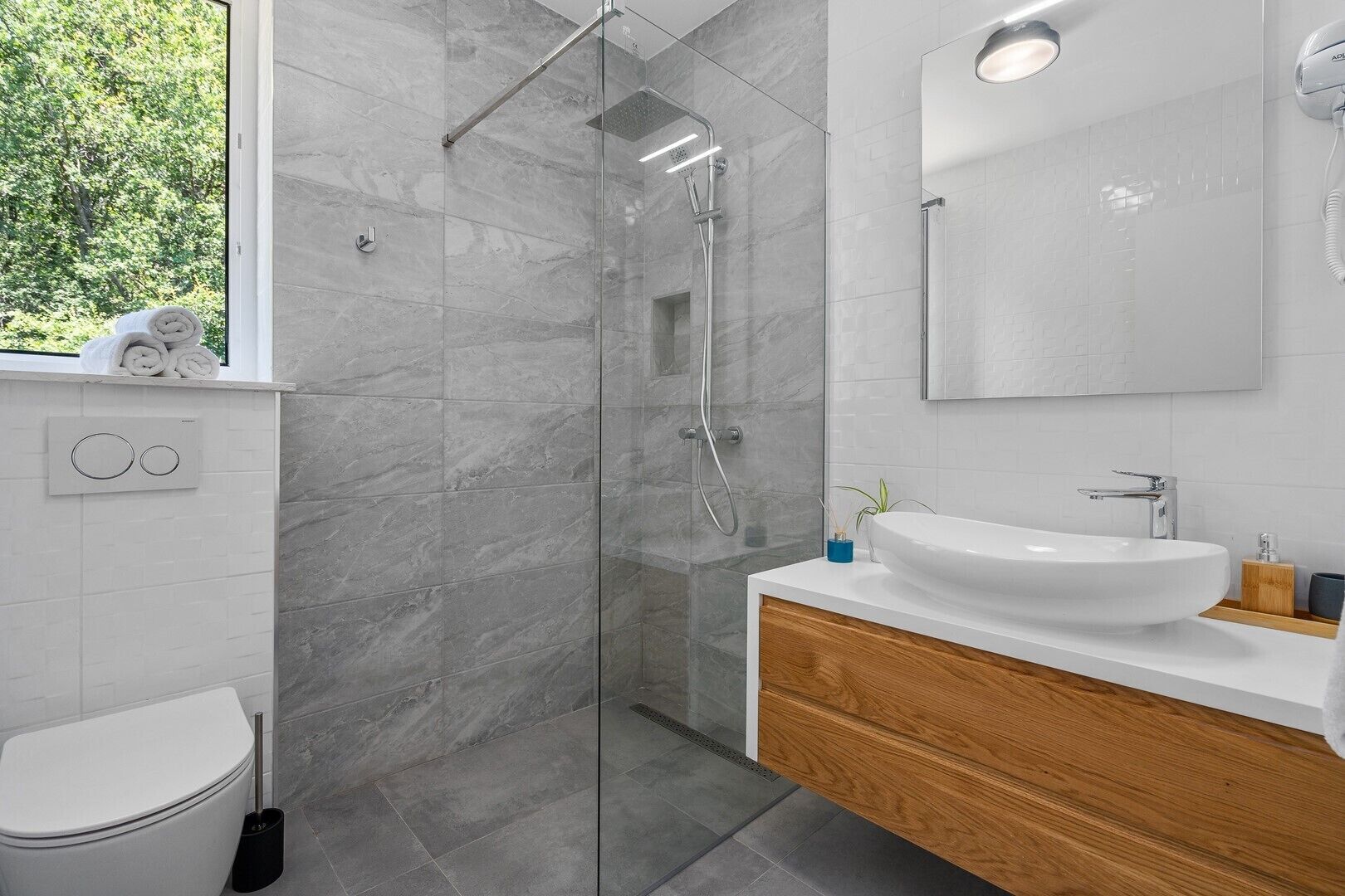 A modern bathroom with a glass-enclosed shower, a white sink, and a wooden vanity.