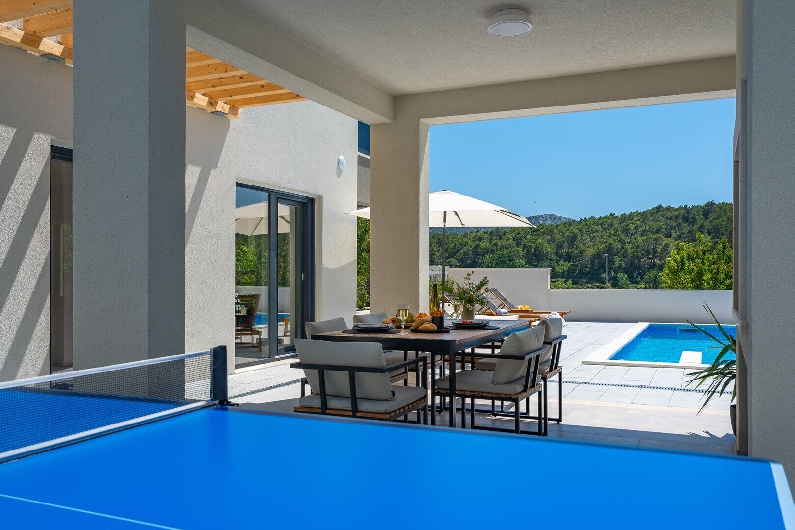 Una mesa de billar con vista a una piscina y un área de comedor con sillas y una mesa.
