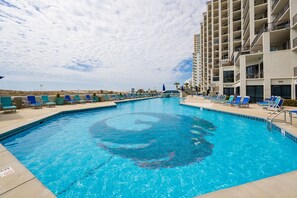 Relax by the rectangular pool surrounded by lounge chairs and umbrellas.