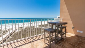 A balcony with a view of the beach and ocean.
