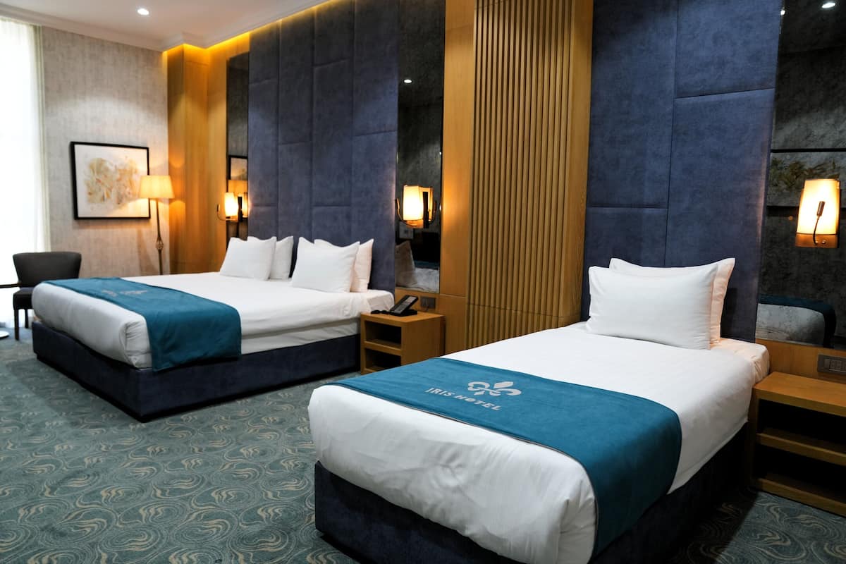 Habitación de hotel con dos camas, un escritorio, una silla y un espejo grande.