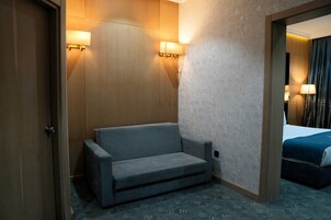 Habitación de hotel con sofá, cama y dos lámparas fijadas a la pared.