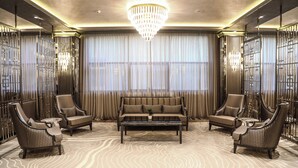 Un salon luxueux comprenant un grand canapé, deux fauteuils, une table basse et un tapis à motifs.