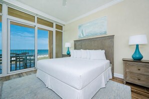 A hotel room with a large bed, two bedside tables with lamps, a view of the ocean, and a painting on the wall. - Phoenix Orange Beach Ii 405 4 Bedroom Condo (Orange Beach)
