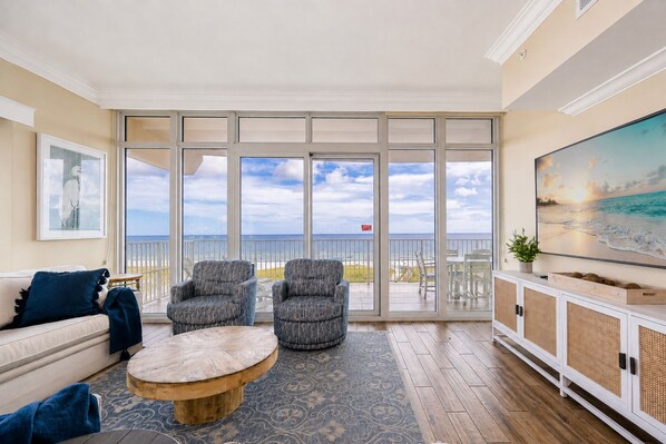 A spacious living room with a large sliding glass door leading to a balcony with a view of the ocean. - Phoenix Orange Beach Ii 405 4 Bedroom Condo (Orange Beach)