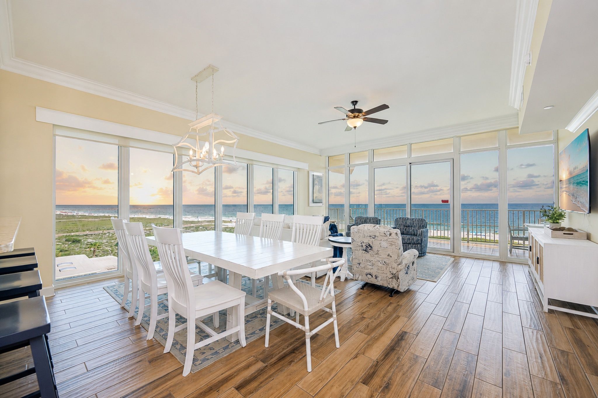 A spacious room with a large dining table, white chairs, and a view of the ocean.