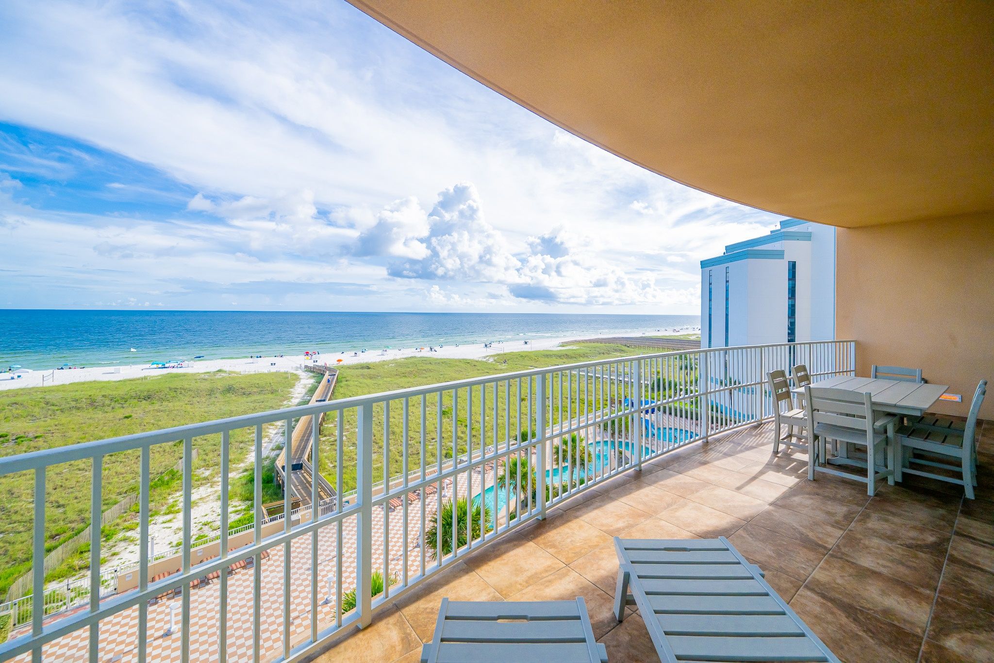 A balcony with a view of a beach and a pool.