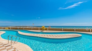 A large, clear swimming pool with a checkered pattern around the edges, a lifeguard chair, and a flag. - Phoenix Orange Beach 1204 3 Bedroom Condo (Orange Beach)