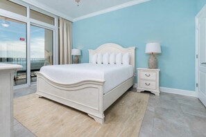 A bedroom with a bed, bedside tables, a nightstand, a view through a sliding door, and a balcony. - Phoenix Orange Beach 1204 3 Bedroom Condo (Orange Beach)