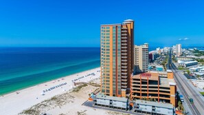 Un hôtel de grande hauteur offrant une vue sur la plage, avec de nombreux étages et un parking.