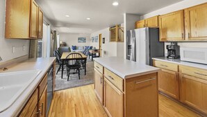 A modern kitchen with wooden cabinets, a stainless steel refrigerator, and a dining area with a table and chairs.