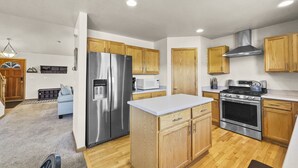 A modern kitchen with wooden cabinets, stainless steel appliances, and a white countertop.