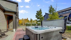 A hot tub in a backyard with a brick pathway and a house in the background.