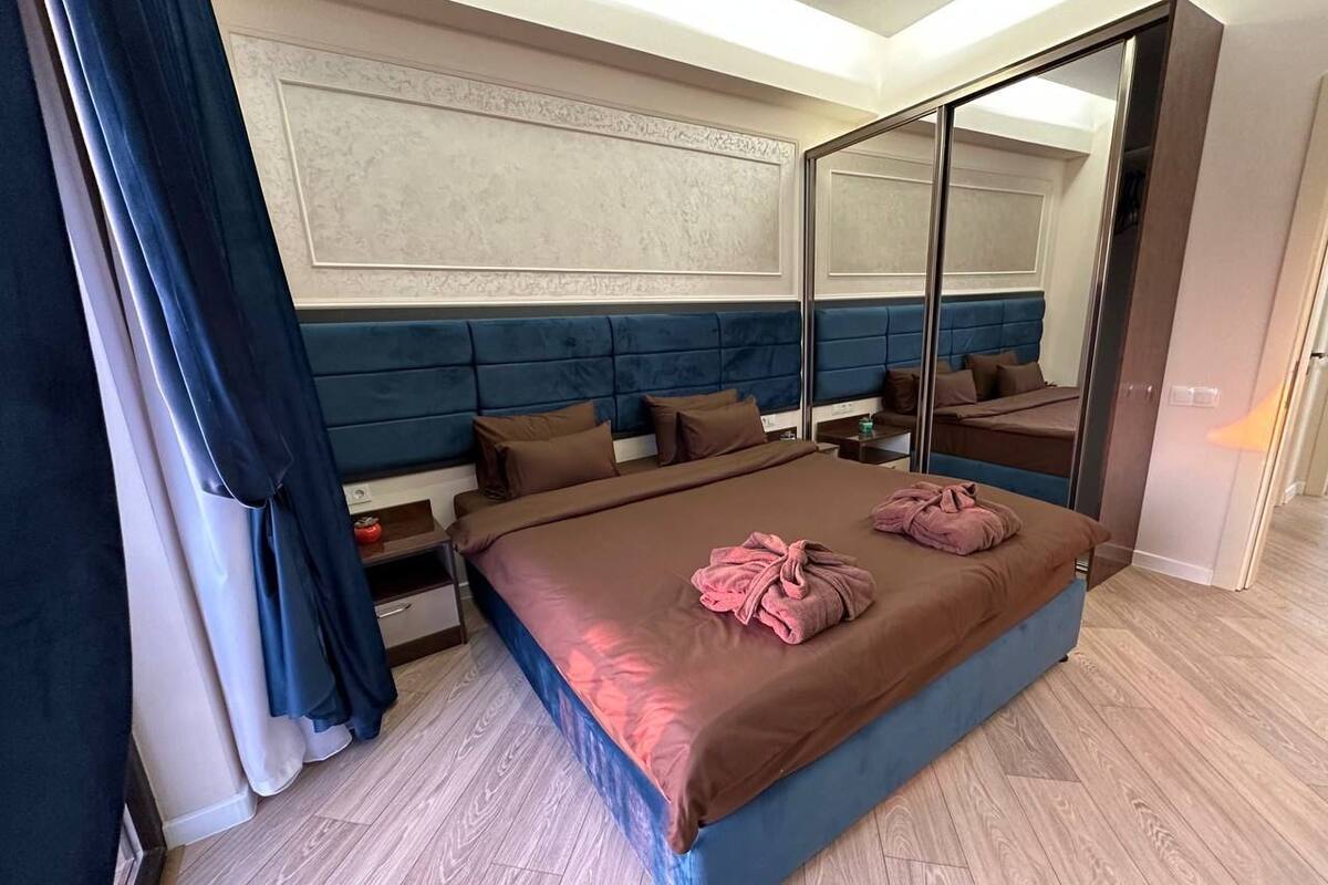 Een moderne hotelkamer met een groot bed, een spiegel en uitzicht op de stad.