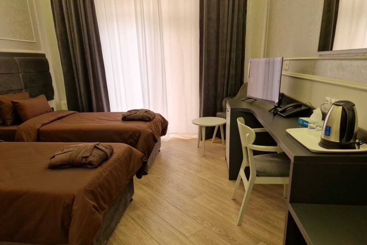 Een hotelkamer met twee bedden, een bureau met een stoel, een waterkoker en een telefoon.