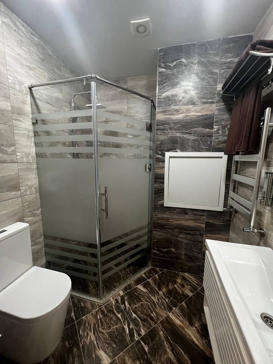 A modern bathroom with a glass-enclosed shower, a toilet, and a bathtub.