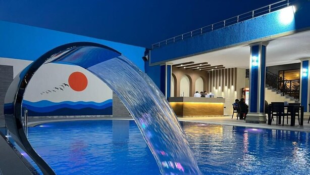 Una piscina con cascada y un área de recepción de diseño moderno.
